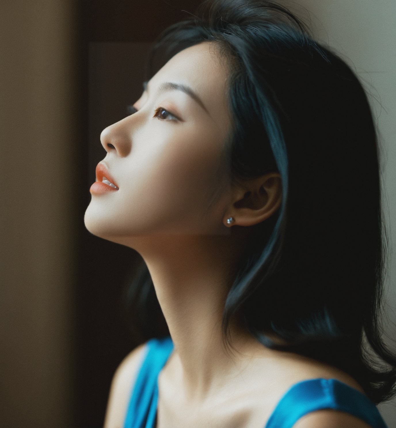 ,woman,Asian ethnicity,profile view,natural light,indoor setting,soft focus,moody,side lighting,contemplative expression,hair clip,blue dress,subtle makeup,young adult,serene,shadows,warm tones,1girl,solo,realistic,closed eyes,blurry,black hair,blurry background,closed mouth,photorealistic,lips,collarbone,upper body,portrait,depth of field,nose,<lora:15-000008:0.6>