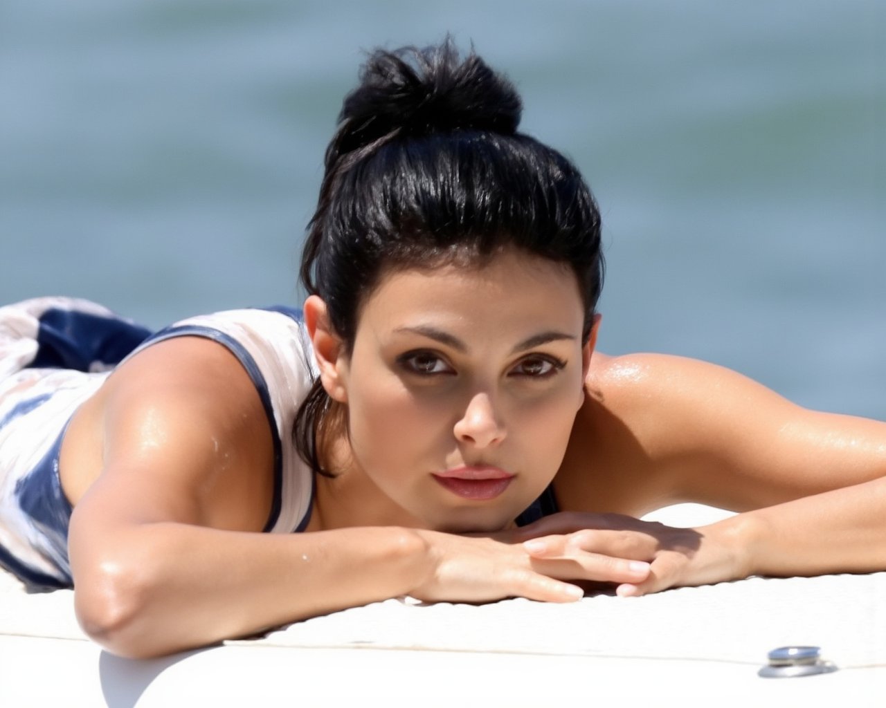 morena_baccarin, A woman is laying down on a boat. The woman hasblack hair and brown eyes. She is wearing a white and blue tank top. Her hands are resting on her face. The boat is white and there is water behind the woman, <lora:MorenaBaccarinF1D:1>