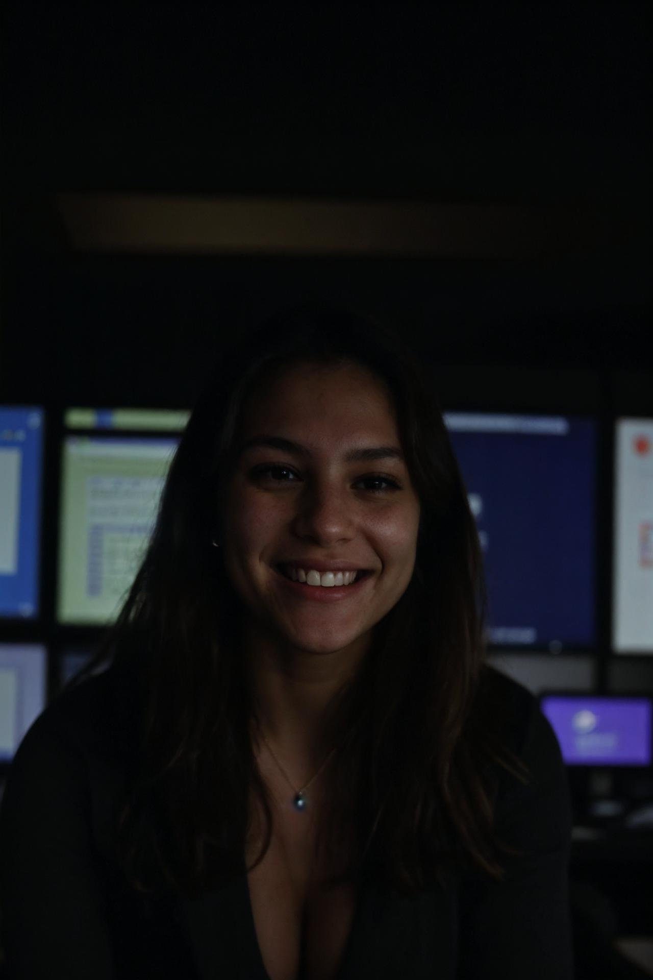 A female social worker having fun in a dark room surrounded by computer screens, poor quality photo, blurry, (smiling:0.5), (soft lighting, high detailed skin:1.1)