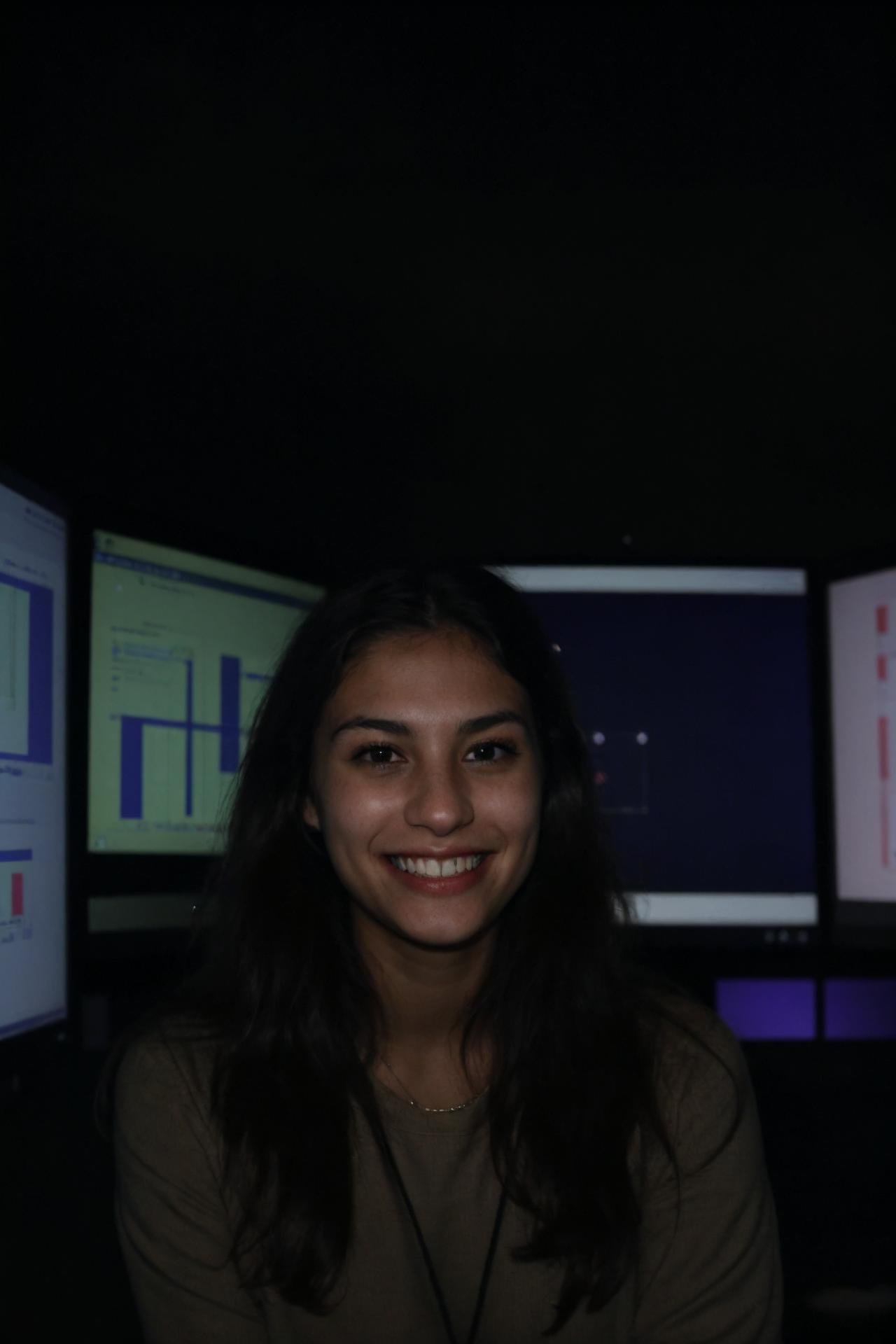 A female social worker having fun in a dark room surrounded by computer screens, poor quality photo, blurry, (smiling:0.5), (soft lighting, high detailed skin:1.1)