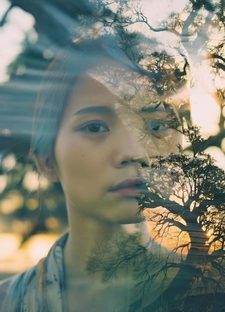 A double exposure film portrait showcasing a young woman with a contemplative expression superimposed with the intricate details of an ancient tree. The blend of human emotion and natural elements on film creates a poetic and surreal visual narrative.,sunset,