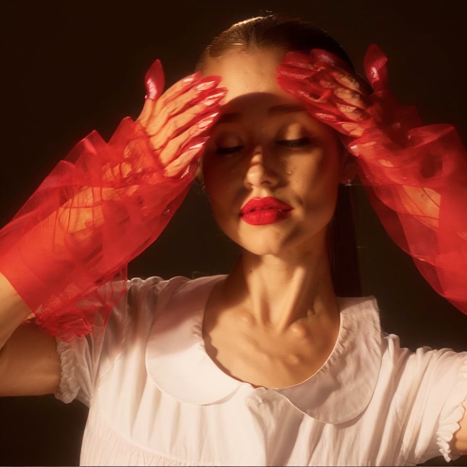 a woman, red gloves, white shirt, brown background, smooth skin