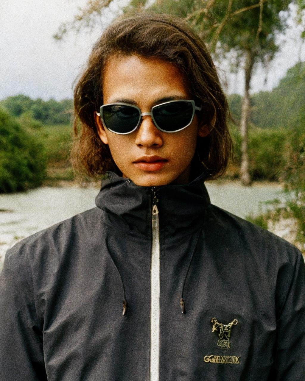 ,black jacket,sunglasses, detailed face, masterpiece,gorpcore,80mm f/11 on kodak ektachrome e100, soft focus, film grain, muted colors,swamp,jungle,,psychedelic,  <lora:gorpcoreLORA:1> 