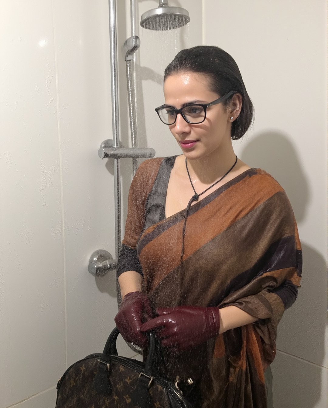 A photo of a wet soaked woman standing under a shower. teacher  in saree and full sleeve blouse and shawl, clings to her body. Her short bobbed hair frames her bespectacled face. Wet clothes, tinted black eyes, and pursed lips convey a sense of reserve. She holds a Louis Vuitton handbag with both hands, wearing leather gloves