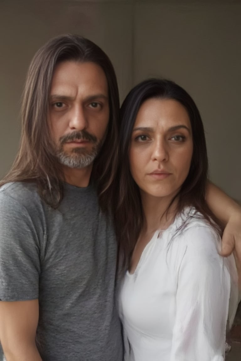 Gasty stands tall on the left, his grey t-shirt and jeans a casual contrast to Paola's crisp white top and brown boots on the right. Both gaze directly at the viewer, their features illuminated by soft, natural light. Gasty's long, brown locks cascade down his back, while Paola's straight black hair falls like a curtain along her shoulders, framing their profiles against a subtle background.