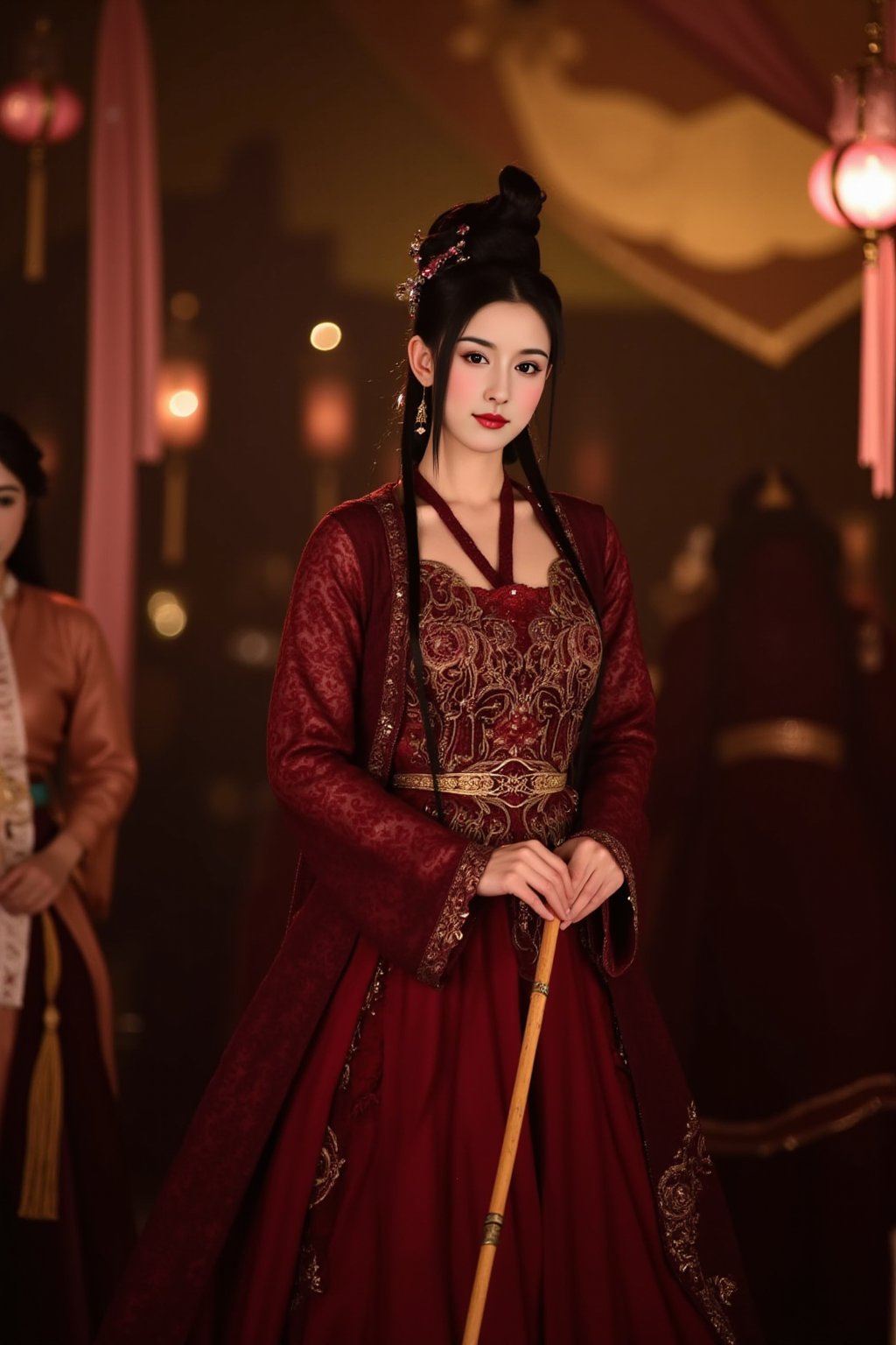 cfairy,
This photograph captures a young East Asian woman in traditional attire, standing indoors in a dimly lit setting. The woman has a fair complexion and long, straight black hair styled in an elegant updo with loose strands framing her face. Her attire is an elaborate, deep red silk gown adorned with intricate golden embroidery and lace detailing. The gown features a high collar, long sleeves, and a fitted bodice that flares out into a full skirt. She holds a long, thin wooden stick in her right hand, adding an element of formality to her posture.

In the background, several other women dressed in similar traditional attire are visible, suggesting a cultural or historical event. The background is softly lit, with warm tones from hanging lanterns and draped fabric, creating a cozy and intimate atmosphere. The setting appears to be indoors, possibly a large tent or a traditional banquet hall, with blurred elements suggesting a festive or celebratory occasion. The overall mood of the photograph is serene and dignified, capturing a moment of cultural significance and elegance. EstherYu.