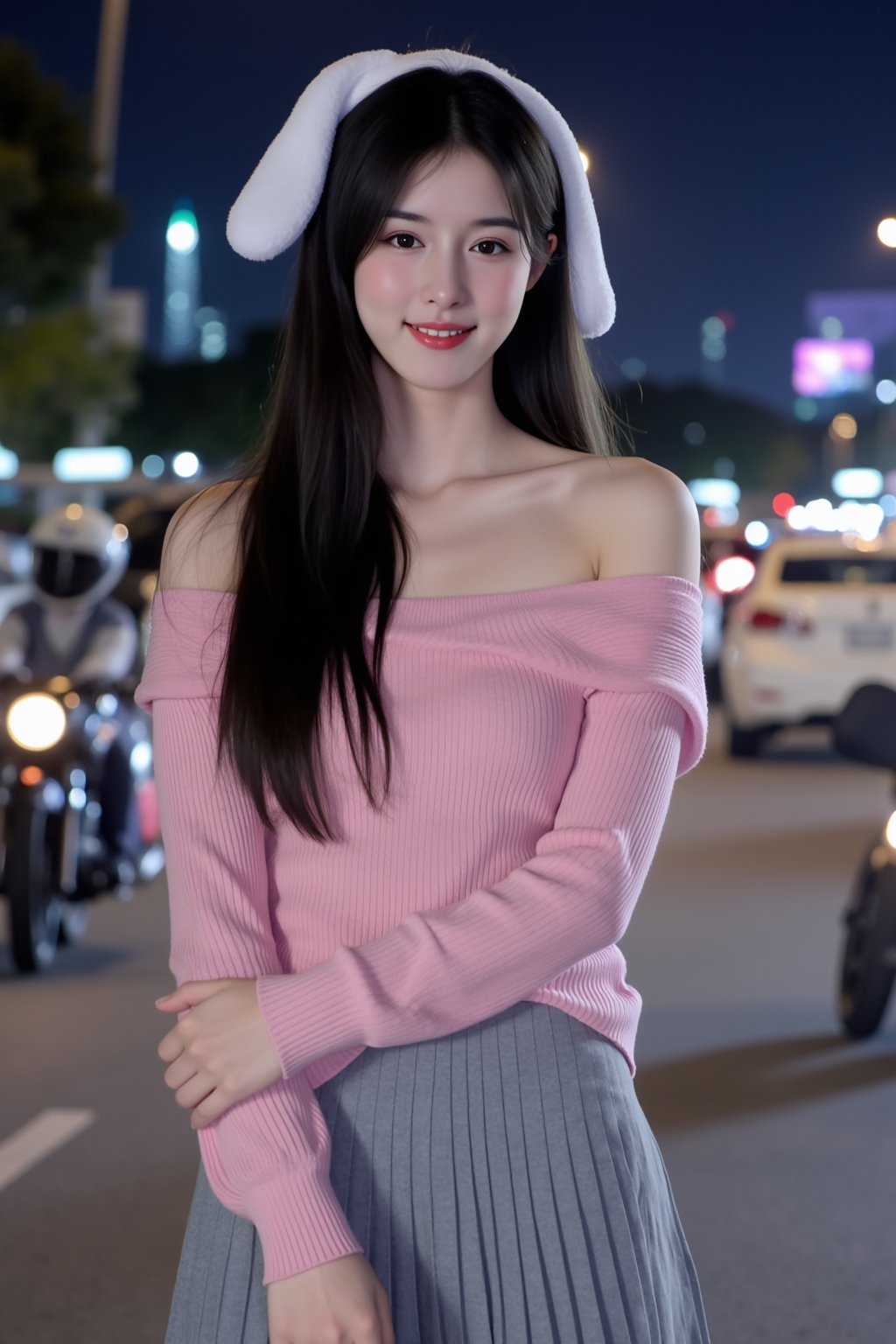 The image is a portrait of a young woman standing in front of a city skyline at night. She is wearing a pink off-the-shoulder sweater and a gray pleated skirt. Her long dark hair is styled in loose waves with white bunny ears and she is looking directly at the camera with a slight smile on her face. The background is blurred, but it appears to be a busy street with cars and motorcycles. The overall mood of the image is casual and relaxed.
