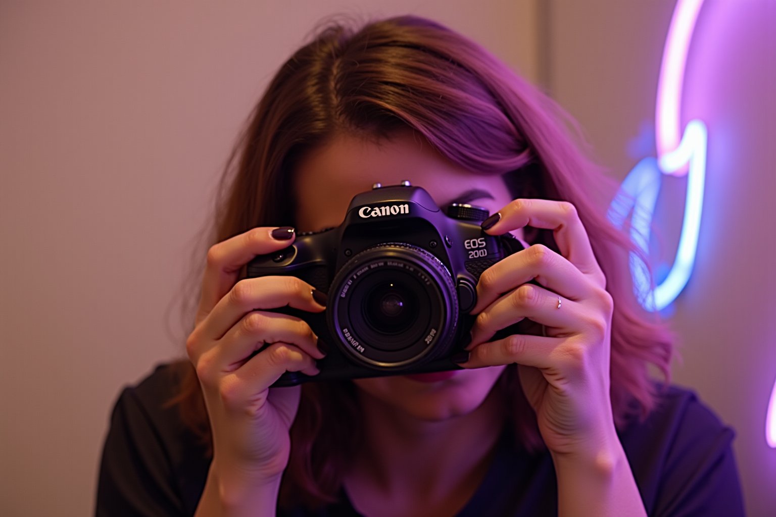 A warm sepia-toned overlay captures the nostalgic and timeless essence of the scene. The subject is a person with chestnut hair, holding a Canon EOS 200D DSLR camera, poised to take a photograph. The camera's black body contrasts with the warm tones of the hair and the soft, neutral background. The person's hands, with manicured nails painted in a dark shade, are steady and skilled, suggesting a familiarity and passion for photography. A blurred background isolates the subject, focusing the viewer's attention on the anticipation of the shot to come. Soft, diffused lighting casts gentle shadows that contour the subject's features and the camera, adding depth and dimension to the image. Neon lights in purple and blue create a dynamic backdrop, introducing an unexpected splash of color to the otherwise warm scene. This touch of modernity adds a layer of contrast, emphasizing the subject’s quiet concentration, the thrill of the capture, and the beauty of the everyday. The neon glow subtly interacts with the sepia tones, casting colorful reflections and enhancing the depth and mood of the scene.