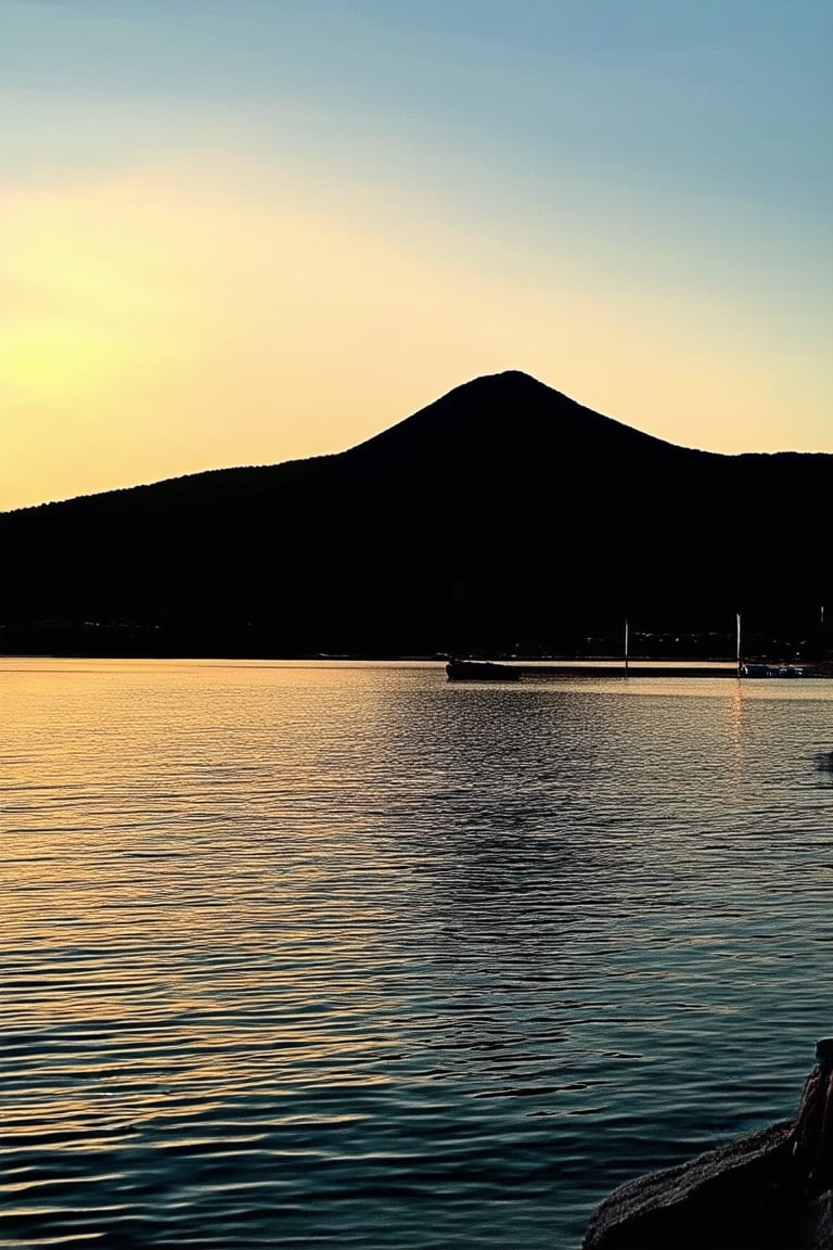 A serene Mandana Koka lakefront scene: A tranquil water's edge at sunset, with the warm golden light casting a gentle glow on the calm lake's surface. In the distance, a majestic mountain range stretches towards the sky. A few boats are moored along the shore, adding a touch of serenity to the peaceful atmosphere.