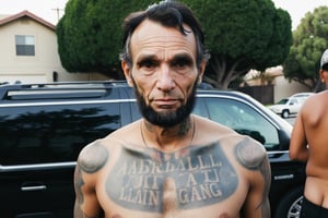 Candid Street Photo. Closeup shot of Abraham Lincoln as a Latino Gang member. Shirtless, tattooed. Busy street of Los Angeles. Canon 5d Mark 4, Kodak Ektar