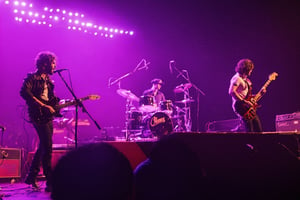 a band is performing on stage with a man playing guitar.
