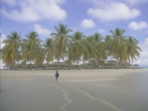 RAW photo, 8k uhd, dslr, outdoor lighting, full sun, high quality, film grain, Fujifilm XT3, landscape, beach scene, very few clouds, sparse white clouds in the sky, tropical island covered with lush green palm trees, one ancient stone tower dominates the horizon, stone tower in the center of the background of the picture, a lush green palm tree forest, a forest of lush green palm trees, turquoise water, white sand, one man walking on the narrow beach, sand is clear except for footprints left by the man, wide angle shot, camera 0.25 mile away from the beach, the man is walking out of the water toward the trees, camera is at a low altitude, camera is over the water, camera is pointed at the island