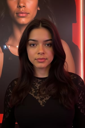  A young woman stands confidently against a movie poster backdrop, her gaze directed straight at the camera, exuding an air of confidence and allure, She wears a black top with a lace pattern, her features softly highlighted by even lighting, Off-center placement draws the viewer's eye towards her, while a subtle hint of a man in the background adds depth to the scene, The movie poster suggests a possible movie theater setting, 