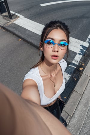 a beautiful female model, a beautiful young woman outdoors in an urban setting. She is wearing small black sunglasses with blue reflective lenses, a white t-shirt with a low neckline and lace trim. She has a small necklace with a pendant. The background features an asphalt road with crosswalk lines, giving the impression of a busy city. The image is taken from a high angle, possibly as a selfie with her arm extended.