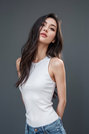 a beautiful female model, a beautiful young woman standing against a grey backdrop. They are wearing a white sleeveless top and blue jeans.