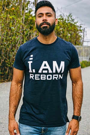 Macho Guy wearing a T-shirt. The words "I am reborn" and "2023" are printed on the T-shirt.