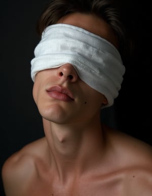 Fine art studio portrait of a handsome young man, partially blinded by a white linen cloth covering his eyes. His face is in close-up, with parted, fleshy full lips, slightly open to reveal a hint of teeth. A small mole and a few freckles add natural detail to his skin. Set against a dark backdrop, soft studio lighting enhances his beautiful male features, casting gentle highlights across his collarbone and face. The lighting and shadows emphasize texture and subtle details, creating an intimate, high-quality image with an evocative atmosphere.,perfection style v3