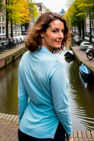 A mature, red-headed woman stands confidently in front of a canal-side backdrop in Amsterdam's charming Holland. She wears a sultry expression, her bright locks cascading down her back as she gazes out at the picturesque cityscape. Soft sunlight illuminates her features, casting a warm glow over the entire scene.