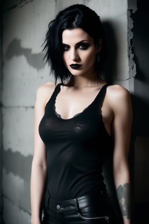 Studio photography: A moody, high-contrast shot of a stunning goth woman posing confidently in front of a distressed concrete wall. She wears a tight-fitting tank top without a bra, her porcelain skin and raven hair drawing attention to her striking features. The analog photograph has a warm, film-like quality, with subtle grain and texture. Her eyes seem to pierce through the darkness as she gazes directly at the camera. The framing is tight, with the subject's body forming a diagonal line that leads the viewer's eye to her enigmatic expression.