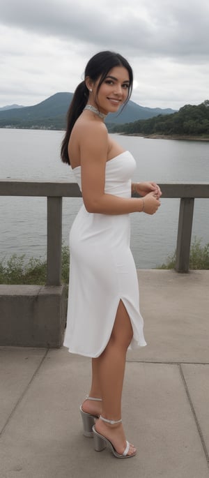 Generate hyper realistic image of a woman standing on a concrete platform with a serene body of water and a distant mountain range in the background. She gazes directly at the viewer with a warm smile. Her left hand rests gently on her right hand. She is dressed in a white strapless gown with a choker necklace around her neck. Her hair is styled in a sleek bob, and her black hair is pulled back in a ponytail. Her eyes are accentuated with dark brown eyeshadow, and she wears silver high-heeled sandals. The sky is scattered with white clouds.