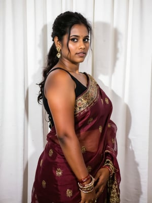 a medium-sized sexy indian woman stands in sidewise in front of a white curtain. She is dressed in a black sleeveless blouse with a maroon sari adorned with gold embroidery. Her hair is pulled back in a ponytail, and she is adorned with a pair of dangling earrings. Her bangles are gold, adding a touch of contrast to her dress. The backdrop is a stark white, creating a stark contrast to the woman's outfit.,photorealistic,Anupama, Warm Lighting,TamannaFlux, IMG0095.HEICl Viewing at camera in a  sensual way,Gil25yo