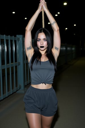 Closeup half body torso view, outdoor night time symmectreical portrait of an outdoor skinny but athletic extremely pale female prisoner wearing a dark gray sleevless shirt. Her armpits are sweating badly. She is tied down to the restraint chair in prison, with her arms tied very high to the ceiling. She is in a situation where she is strapped down to a prison chair with her arms raised by a rope. She is also wearing very loose, flappy, dark gray prison shorts. Also wearing long dark gray prison pants She has arm tattoos, long black colored hair, black lipstick, bright blue eyes, sleeve tattoos on both arms remember this photo is taken at night time, with a very bright flash shining on her body, she is very sweaty as well duet no air conditioning

she has very msucular arms, deep hollow armpits , very tight athelte body type