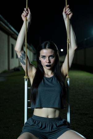 Closeup half body torso view, outdoor night time symmectreical portrait of an outdoor skinny but athletic extremely pale female prisoner wearing a dark gray sleevless shirt. Her armpits are sweating badly. She is tied down to the restraint chair in prison, with her arms tied very high to the ceiling. She is in a situation where she is strapped down to a prison chair with her arms raised by a rope. She is also wearing very loose, flappy, dark gray prison shorts. Also wearing long dark gray prison pants She has arm tattoos, long black colored hair, black lipstick, bright blue eyes, sleeve tattoos on both arms remember this photo is taken at night time, with a very bright flash shining on her body, she is very sweaty as well duet no air conditioning