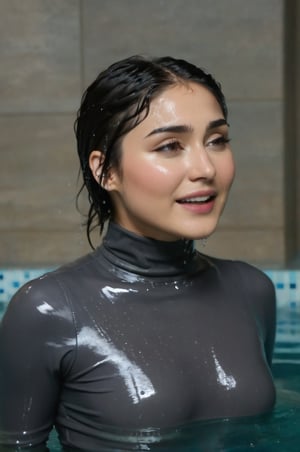 Daniella Pineda, emerging from the water. Her head and shoulders are visible above the surface of water. She looks surprised but smiling, her dark grey turtleneck top wet and clinging to her, with water droplets sparkling around her. She is in the middle of an indoor pool and splashes from her emergence, fully drenched, dripping wet, wet hair, face wet, face drenched