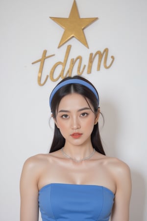 a woman wearing a blue strapless dress and a headband.The backdrop is a stark white wall, adorned with a gold star and the words "TDNM" written in a cursive font.,wonder beauty