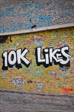 “Photo of a wall in the city. On the wall  we see detailed graffiti, the graffiti text reads "10K LIKES".”,text say's