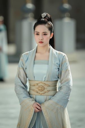 cfairy,
This is a photograph of a young East Asian woman standing in a serene outdoor setting. She is dressed in traditional Chinese attire, specifically a luxurious, light blue robe with intricate golden embroidery. The robe is adorned with a high collar, and the sleeves are long and flowing, featuring a pattern of gold lines and geometric designs. A golden belt with a central ornate buckle cinches her waist, and she wears a matching gold sash that drapes down her front. Her hair is styled in a classic updo, adorned with a delicate, silver hairpin at the top, which adds a touch of elegance. 

The background is slightly blurred, but it appears to be a courtyard or garden area with large, rectangular, stone structures and a faint glimpse of a person in traditional attire, possibly a guard or a fellow performer. The lighting is soft, casting a gentle glow over the scene, suggesting a peaceful, possibly historical or cultural event. The overall mood of the image is one of grace and refinement, capturing the beauty and tradition of traditional Chinese attire. xiaofeng.