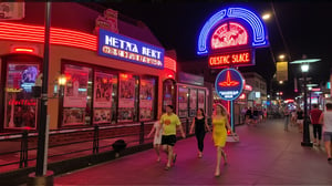 A sultry blonde bombshell, hair styled in a Farrah Fawcett-esque flip, sashays down the vibrant sidewalk under the warm glow of neon lights. A snug yellow sundress hugs her curves as she confidently strides through the bustling street, high heels clicking out the rhythm. Retro-style billboards and neon signs create a lively backdrop as she disappears into the crowded summer night scene.