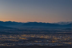 A dense layer of blue clouds illuminated in royalblue from above, a small golden sun, light gray mountains in the distance on the horizon among which power plants and industrial buildings can be seen, closer gray mountains on the horizon among which power plants and industrial buildings can be seen, black mountains on the horizon among which power plants and industrial buildings can be seen,