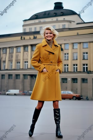 DDRFashion Blonde woman smiling and wearing a heavy mustard coat in Berlin near Alexanderplatz in front of a neoclassical building. Black boots, Cold War style. Burda magazine cover. Fashion 1980s.