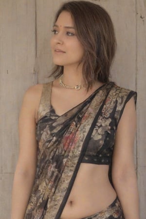 an indian woman with dark brown hair, wearing a black sleeveless blouse and a saree with a floral print. She is wearing a silver heart-shaped necklace, adorned with silver earrings. The woman's hair is pulled back, framing her face. The backdrop is a stark white wall, with a light brown wooden door on the left side of the frame.,Sexy Saree