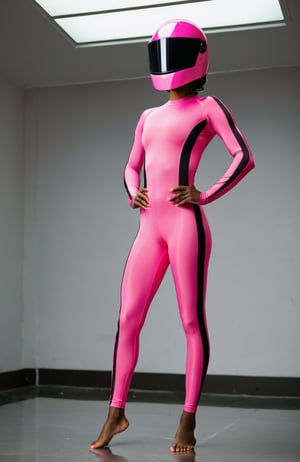 A black woman in a no neck pink spandex unitard with black stripes on the sides, wearing a pink faceless helmet, stands barefoot in a room,