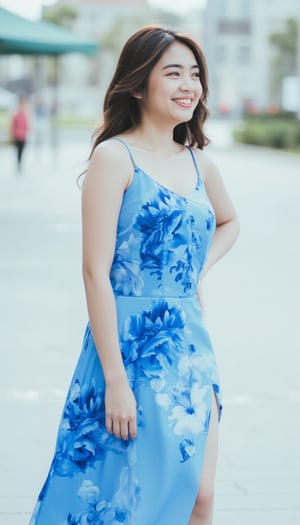 A young Asian woman stands on a white sidewalk, her left arm resting on her hip. She is facing the right side of the frame, her right arm is slightly bent at the elbow. Her left arm is draped in a sleeveless blue dress, adorned with a pattern of blue and white flowers. Her brown hair is cascading down her back, adding a pop of color to her face. The backdrop is blurred, creating a stark contrast to the woman's dress.