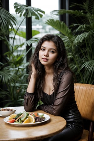 A cinematic photo of a young Indian woman with wavy hair, aged 18, sitting in a tropical-styled cafe eating fruits at evening and posing hot for her photo, she is vering revealing leather outfit. Her eyes are open, and she gives a sexy expression. The overall atmosphere of the image is serene and cinematic, capturing the essence of fashion and beauty. Background  must depict cozy tropical style cafe blurred