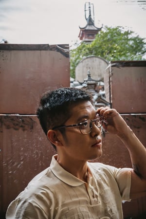 (Asian man, Taiwanese man:1.1), 30 years old, ((male focus)), looking outside, mature, handsome, charming, stylish, dashing, unique personality, (short hair:1.3), (facial hair, stubble), round glasses, white collared shirt, roll up sleeves, perfect proportions, perfect perspective, cinematic lighting, film photography, (portrait, headshot, close-up:1.2), subtropical environment, scenery, historical, heritage, rustic, (Taiwanese temple background, Historical Taiwanese Temple, Lukang Longshan Temple), Hokkien architecture, (orange tiled roof, upward curve ridge roof, wooden structure), stone base, red brick wall, trees,man 