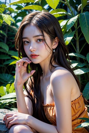 a portrait of a young woman sitting on a rock in a tropical setting. She is wearing a strapless orange dress with a floral pattern and her hair is styled in loose waves. The woman is holding a large green leaf in her right hand and is looking off to the side with a serious expression on her face. The background is blurred, but it appears to be a wooded area with trees and foliage. The lighting is soft and natural, creating a dreamy atmosphere