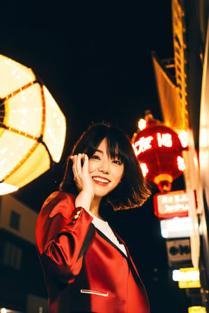 A young Asian woman, short hair, wearing a red jacket and a white t-shirt with Japanese text, necklace, standing on a busy Tokyo street at night, with Tokyo Tower clearly visible in the background, illuminated city lights, traditional Japanese lanterns, urban style, night photography, candid pose, low angle shot, with a hint of film grain, striking a cool pose, confident stance, hands raised to the sides of her head, dynamic and stylish.
