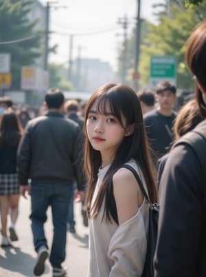 A young Korean girl with long hair and no sleeve top stands amidst a crowd of people walking in both left and right directions. She walks towards the right side, capturing a scene by looking forward at someone passing her. The framing is from a slight angle, emphasizing her figure against the blurred background. Soft natural light illuminates her face, while the surrounding atmosphere remains hazy.