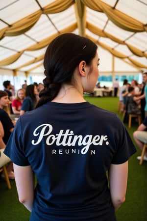 Wide angle candid shot of an 30 year old woman wearing a dark blue teeshirt with a logo for "Pottinger Reunion" emblazoned on it in white sot from behind. The subject's black hair is long and in a plait, and her skin is pale and freckled. The woman is standing in a beautifully decorated marquee.