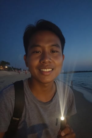 A handsome Malay young man lit by a flashlight is taking selfie at the beach