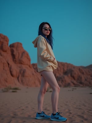 A young East Asian woman with a long, layered haircut and beige hoodie stands in a three-quarter view on sandy terrain, surrounded by rocky formations under a clear sky, now illuminated by a warm, low-key neon glow at night, as she gazes directly at the camera with an air of mystery, her left hand on her hip, wearing black sunglasses, blue sneakers with textured soles, and a hint of blue highlights in her hair, evoking the moody, cinematic style of Wong Kar-wai, with a shallow depth of field, subtle film grain, and muted color grading, shot with a mix of cool and warm tones, and a slight vignette, as if captured on 35mm film.