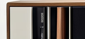 Ultra-detailed close-up of a modern Bluetooth Sangean radio in a luxurious minimalist bookshelf. The radio's elegant wooden grain finish (wooden grain:1.2) wraps around its sides, paired with a black front panel  featuring a sharp digital display showing the time and station. Tactile buttons (buttons:1.2) for tuning and volume catch the light, highlighting their precise layout. The bookshelf, made of rich dark wood with metal accents, contains books , geometric sculptures, and succulents . Soft ambient light casts shadows, enhancing the textures of the wood and the sleek display. The ambiance blends modern sophistication and cozy warmth, with the radio as the focal point.