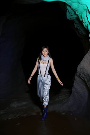 A Korean woman wearing a headlamp, scarf, necklace, rings, bracelets, suspenders, rain boots and sexy low-cut pajamas is rolling in a cave!