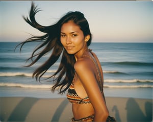 Lifestyle photography of a Native American woman, with dark hair in a high ponytail, having fun at a beach, (full body framing:1.2), with the ocean in the background, under the golden hour light, (shot from below:1.2), on a Polaroid SX-70 with Fujicolor Pro film, in the style of Walker Evans