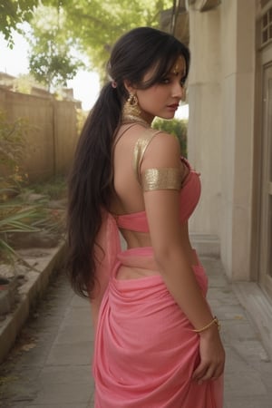 The model is wearing a black saree with a contrasting pink blouse. The saree features a gold border, and the blouse has a halter neck with a back tie and tassels. She accessorizes with statement earrings and a bindi on her forehead. Her hair is styled in a loose, wavy ponytail. The overall look is elegant and contemporary, highlighting traditional attire with a modern twist. The setting appears to be an urban environment with neutral tones in the background, making the colorful saree stand out.