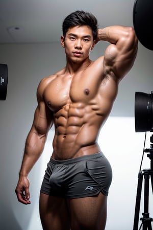 In a dimly lit studio setting, a stunning Asian male model stands confidently against a crisp white backdrop. His chiseled physique is accentuated by sharp lighting that highlights every contour of his muscles. The tight-fitting shorts barely contain the impressive bulge, as he strikes a dynamic pose with a hint of embarrassment on his handsome face. Every detail of his skin is rendered in exquisite human-like accuracy, featuring body hair and dewy, oiled skin that radiates texture. The camera captures his sharp focus and muscular physique in stunning 8K resolution, with physically-based rendering bringing every aspect to life.